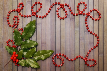 Christmas wooden background with garland and holly leavesの写真素材