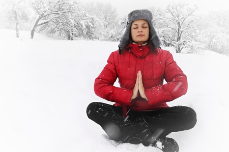 Woman meditating in the lotus position in winterの写真素材