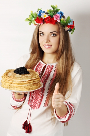 Ukrainian woman holds a plate of pancakes and caviar showing ok gestureの写真素材