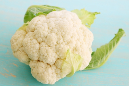Fresh cauliflower on a blue painted wooden boardの写真素材