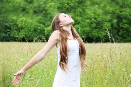 Free young woman on the meadow breathes in deeplyの写真素材