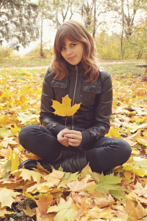 Portrait of a girl sitting on the autumn leavesの写真素材