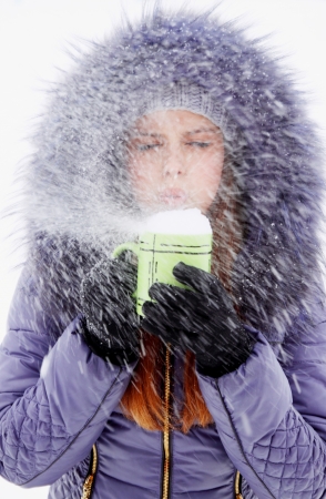 Woman blowing on a cup full of snowの写真素材