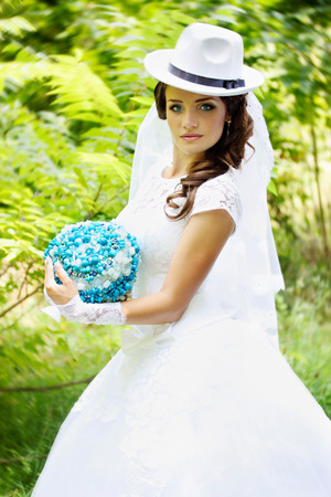 Beautiful bride in a hat with a bouquet of turquoise stonesの写真素材