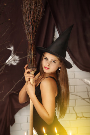 Young beautiful witch  with hat and broomの写真素材