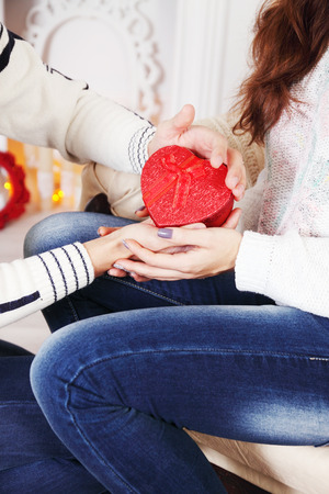 hands of a man and woman holding a heart-shaped boxの写真素材