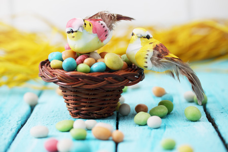 Bird sitting in a small basket on a pile of candies