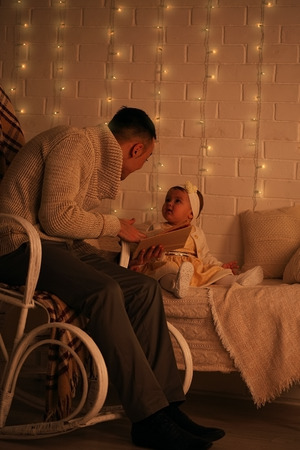 Portrait of loving father reading book together with his daughterの写真素材