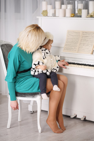 Mother teaching her daughter to play pianoの写真素材