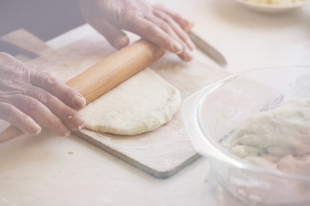 Hands roll the dough on a wooden board. photo toning Pastel