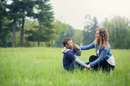 Young mother plays with her son in a meadowの写真素材