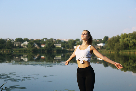 Young girl spreading hands with joy and inspiration facing the sunの写真素材