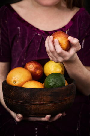 Girl is holding a bowl of citrus fetusの写真素材