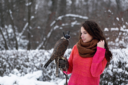 A girl with a falcon strolls in the winter in the forestの写真素材