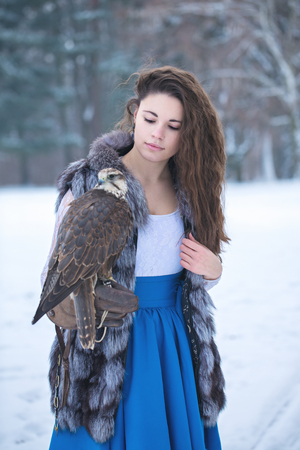 Beautiful woman and falcon in winterの写真素材