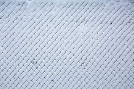 Snow covered fence from the grid. winter backgroundの写真素材