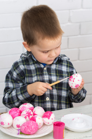 The boy paints Easter eggsの写真素材