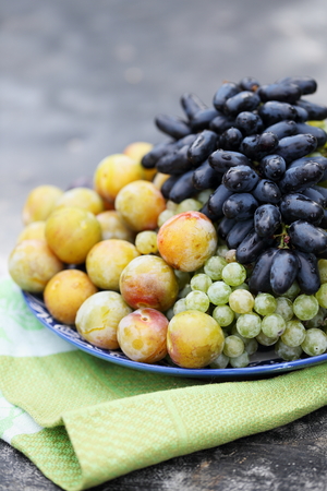 grapes, plums on a plateの写真素材