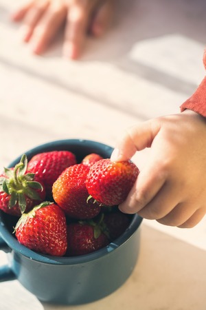 Childs hand takes strawberriesの写真素材