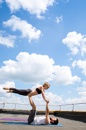 Man and woman are engaged in acro yoga position birdの写真素材