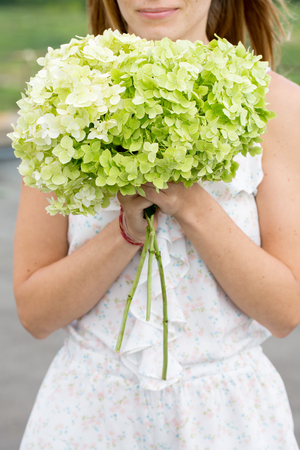 young woman sniffing a flowersの写真素材