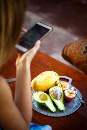 Girl makes photo on smartphone exotic fruitsの写真素材