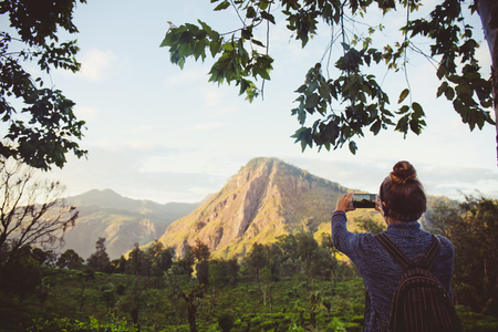 Girl tourist photographing mountains and tea plantations in Sri Lankaの写真素材