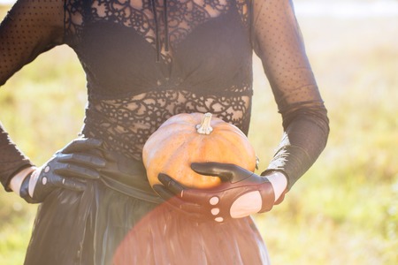 Glamorous young woman in a black dress with a pumpkin. Halloween Conceptの写真素材