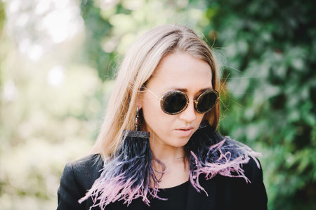 Beautiful blonde in sunglasses in ostrich feather earrings
