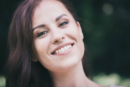 Beautiful young long-haired brunette with a charming white-toothed smileの写真素材