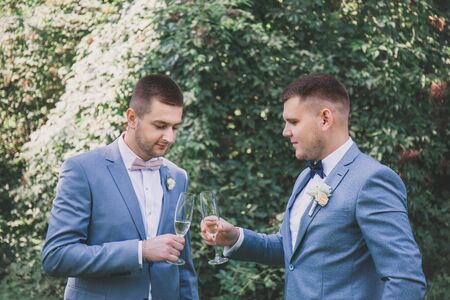 newlyweds with guests drink champagne in the parkの写真素材