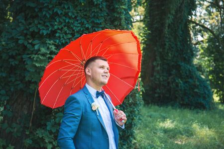 Man in a suit with a red umbrella in the parkの写真素材