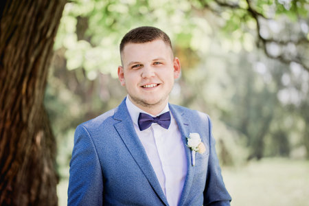 Groom with a bouquet of flowers in his hands waiting for the bride in the parkの写真素材
