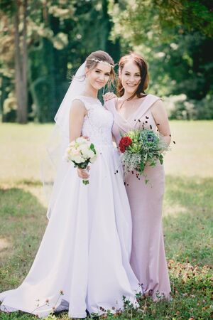 Beautiful girls Bride and bridesmaid with bouquets in the parkの写真素材