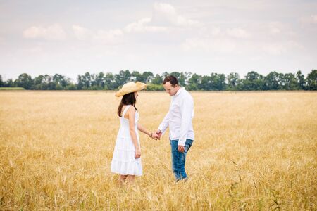 Young couple walking in a golden fieldの写真素材