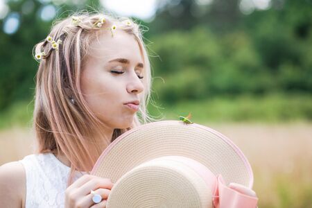 Beautiful young girl holding a hat with a green grasshopperの写真素材