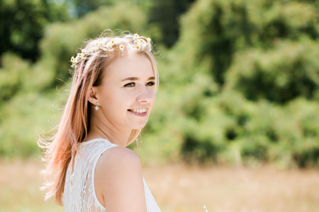Beautiful young woman in a white vintage lace dress with pink hair walks across the meadowの写真素材