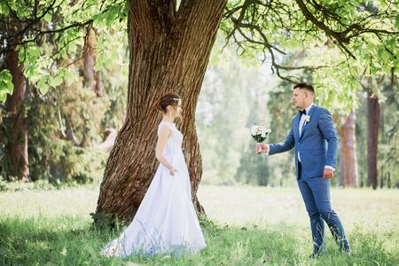 Portrait of the bride and groom with a bouquet of flowers in the parkの写真素材