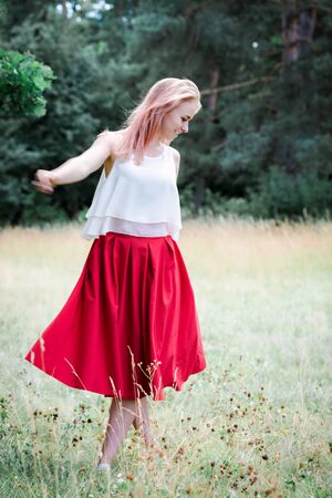 The girl in the red skirt is dancing in natureの写真素材