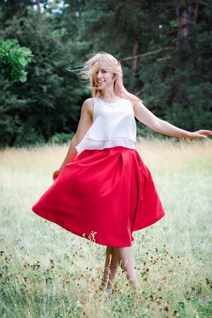 The girl in the red skirt is dancing in natureの写真素材