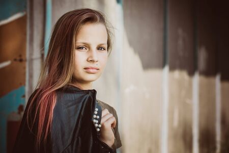 Beautiful brutal teen girl with pink hair and leather jacket in her handsの写真素材