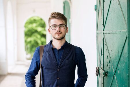 young man with a bag is waiting for a meeting by the old doorsの写真素材