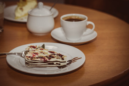 Cake with cherry on a plate and hot aromatic espresso in a cafe