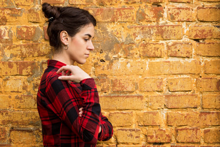 Portrait of a young dark-haired girl against the background of a brick wallの写真素材