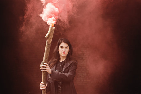 Beautiful witch in black with a smoking stick. Halloween concept