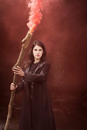Beautiful witch in black with a smoking stick. Halloween concept