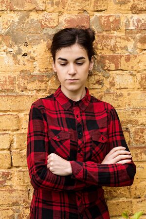 Portrait of a young dark-haired girl against the background of a brick wallの写真素材