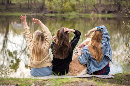 Three girls relaxing by the river with a dog