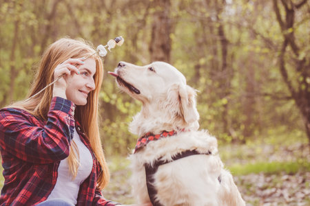Beautiful red-haired young woman with a dog fries marshmallows on a fire