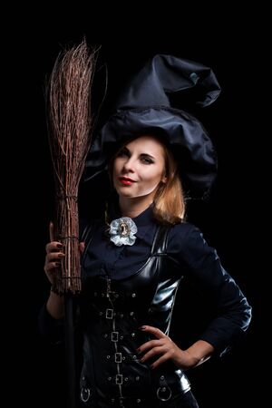 Beautiful witch in a black hat with a broomの写真素材
